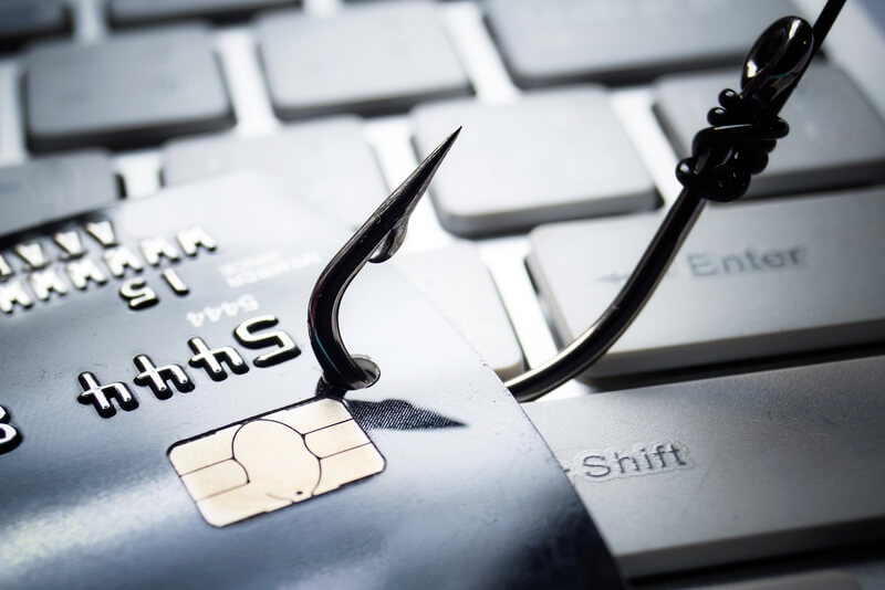 Credit card phishing attack. Credit card with a fish hook on computer keyboard - phishing attack on financial information