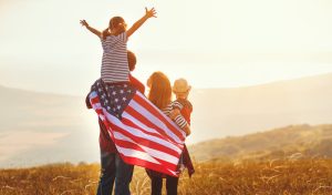 Happy family with the flag of america USA at sunset outdoors