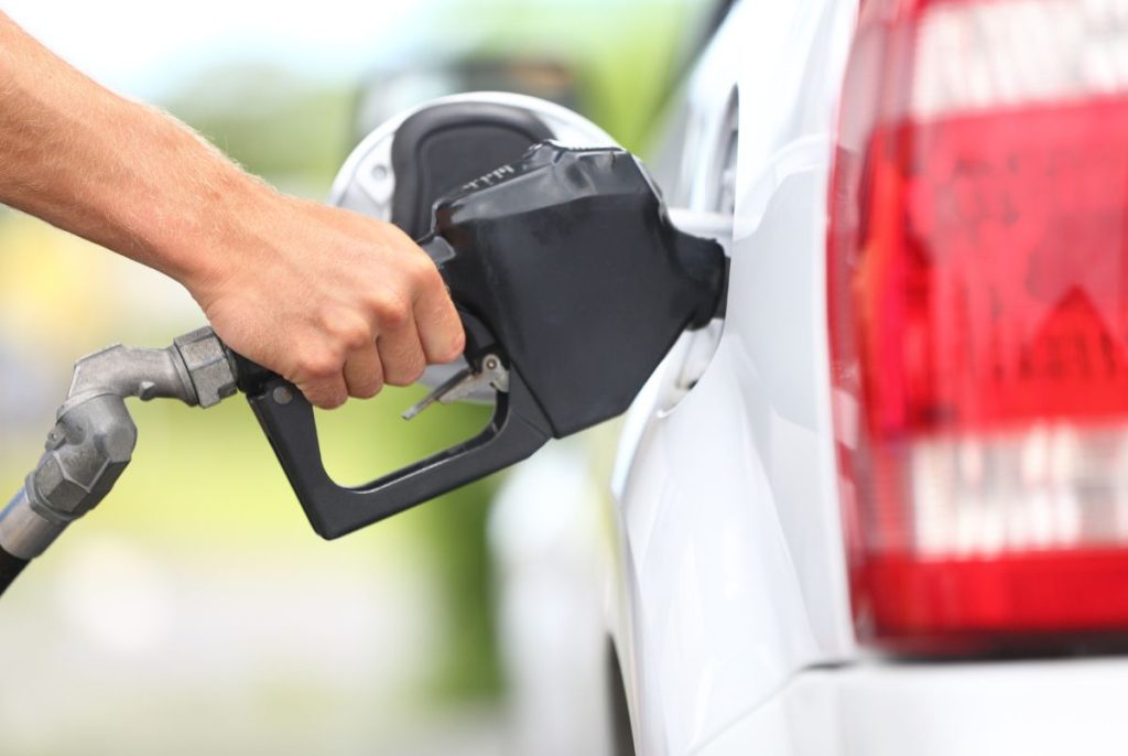 Pumping gas at gas pump. Closeup of man pumping gasoline fuel in car at gas station.