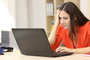 Sad and worried entrepreneur with laptop. Sad and worried entrepreneur working on line with a laptop in an office desk or home
