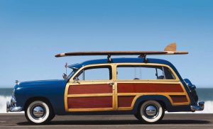 Woody-profile. Side view of woody car with surfboard and surf in background