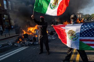 People rioting in Los Angeles, holding up Mexican flags