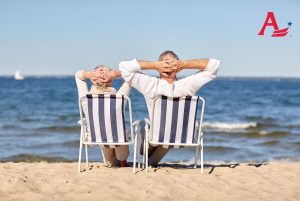 2 seniors relaxing in blue and white stripped beach chairs