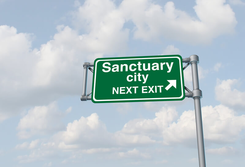Sanctuary city concept and illegal immigration law government enforcement policies as a highway sign directing to welcoming immigrants with no legal status as a 3D illustration.