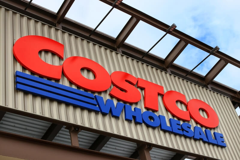Logo of Costco storefront, close up facade entrance cloud blue sky. Wholesale Corporation is largest membership-only warehouse club in USA