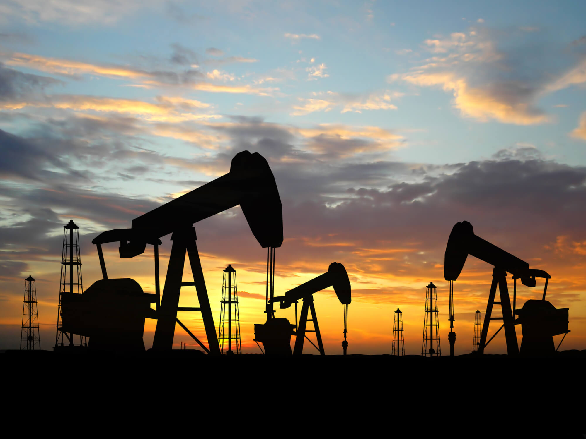 Silhouette oil rigs. Oil rigs silhouette over orange sky