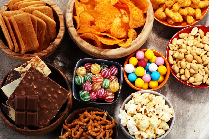 Salty snacks. Pretzels, chips, crackers in wooden bowls. Unhealthy products. food bad for figure, skin, heart and teeth. Assortment of fast carbohydrates food.