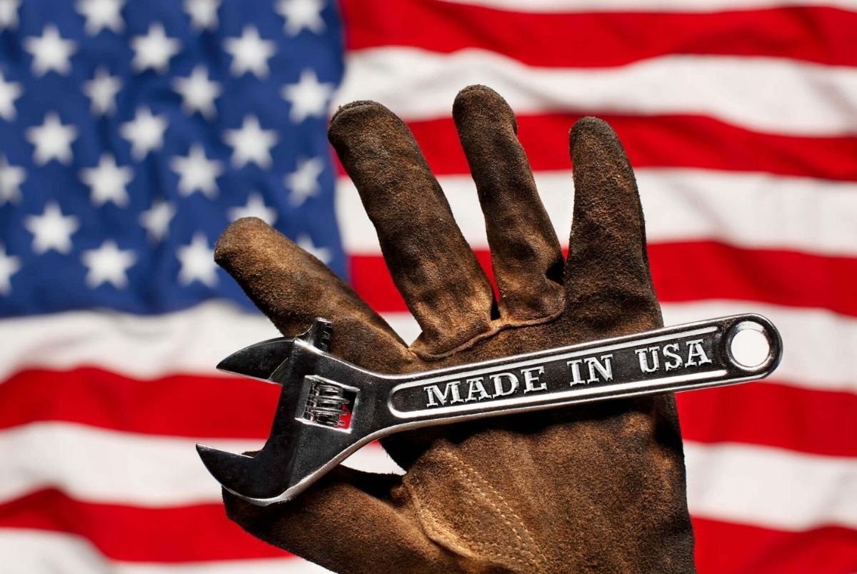Old worn work glove holding adjustable wrench with Made in USA text. American workforce or industry, or America labor concept
