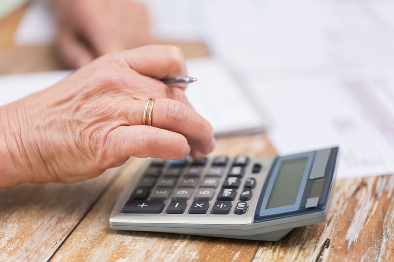 Close up of senior woman counting with calculator.
