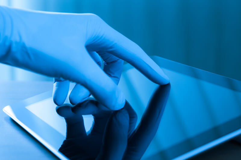 Hand in blue glove touching modern digital tablet