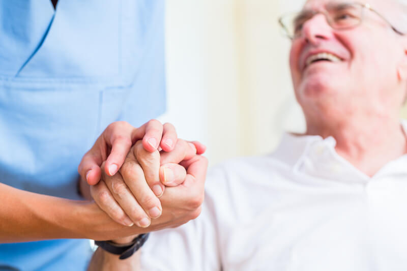 Nurse holding hand of senior men in rest home