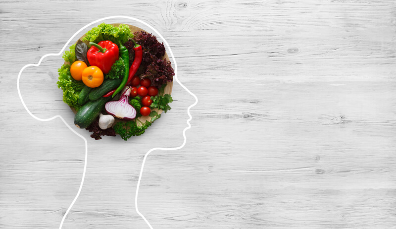 Fresh vegetables in woman head symbolizing health nutrition on gray background