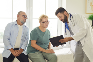 Male doctor explaining prior authorization to senior couple during clinic consultation.