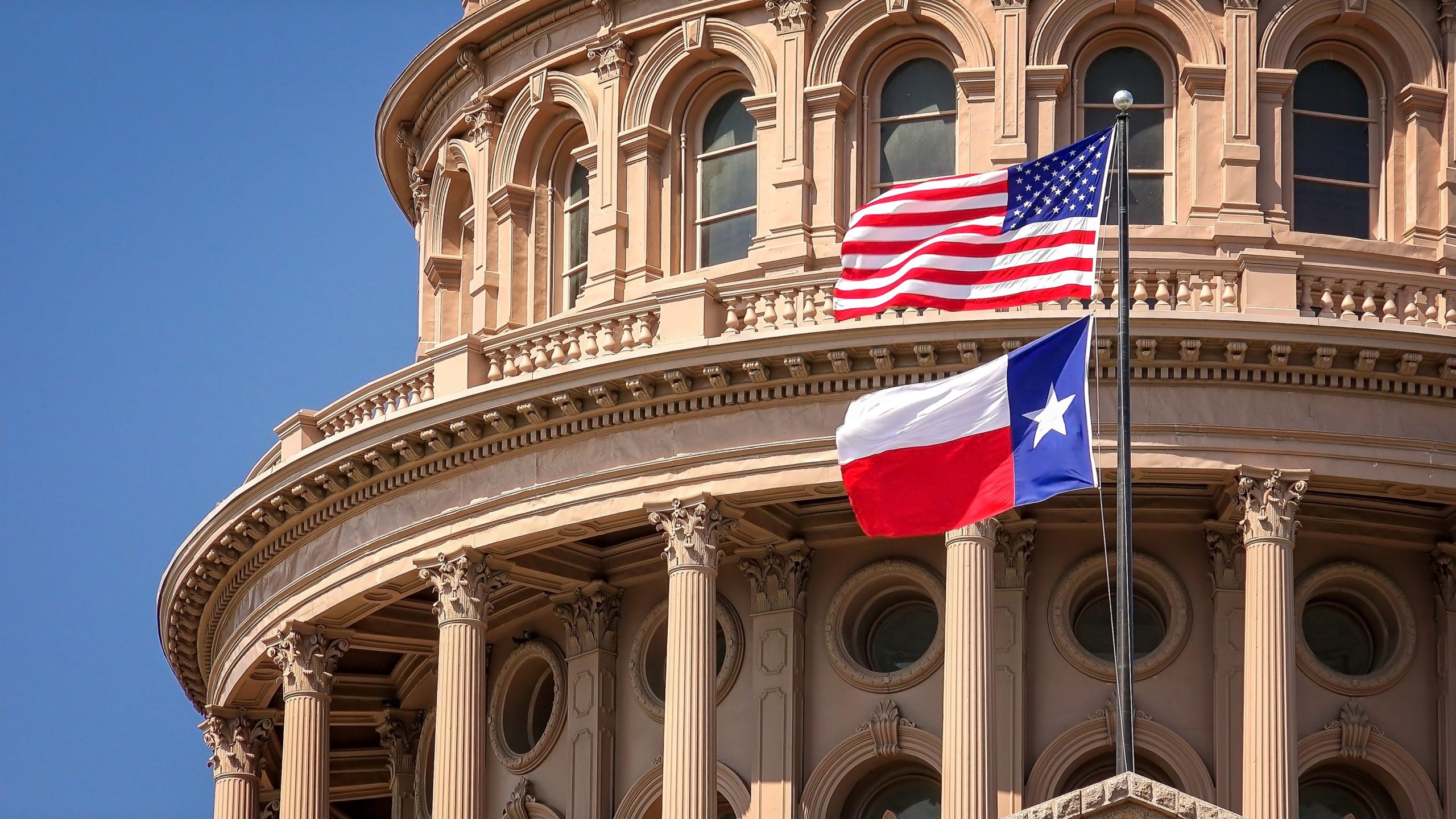 The Chris Larkin ALS Act Expands Medigap Coverage for Texans Under 65. American and Texas Flags Flying at the Texas State Capitol Building in Austin. American and Texas state flags flying on the dome of the Texas State Capitol building in Austin.