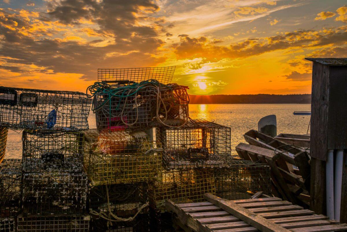 Lobster Traps at Dusk. Scenic waterscape of an evening cloud filled sky over a bay in Maine with lobster traps and other gear on a dock in the foreground.