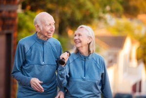 Joyful older couple walking outdoors. Joyful mature couple in matching blue athletic outfits together outside