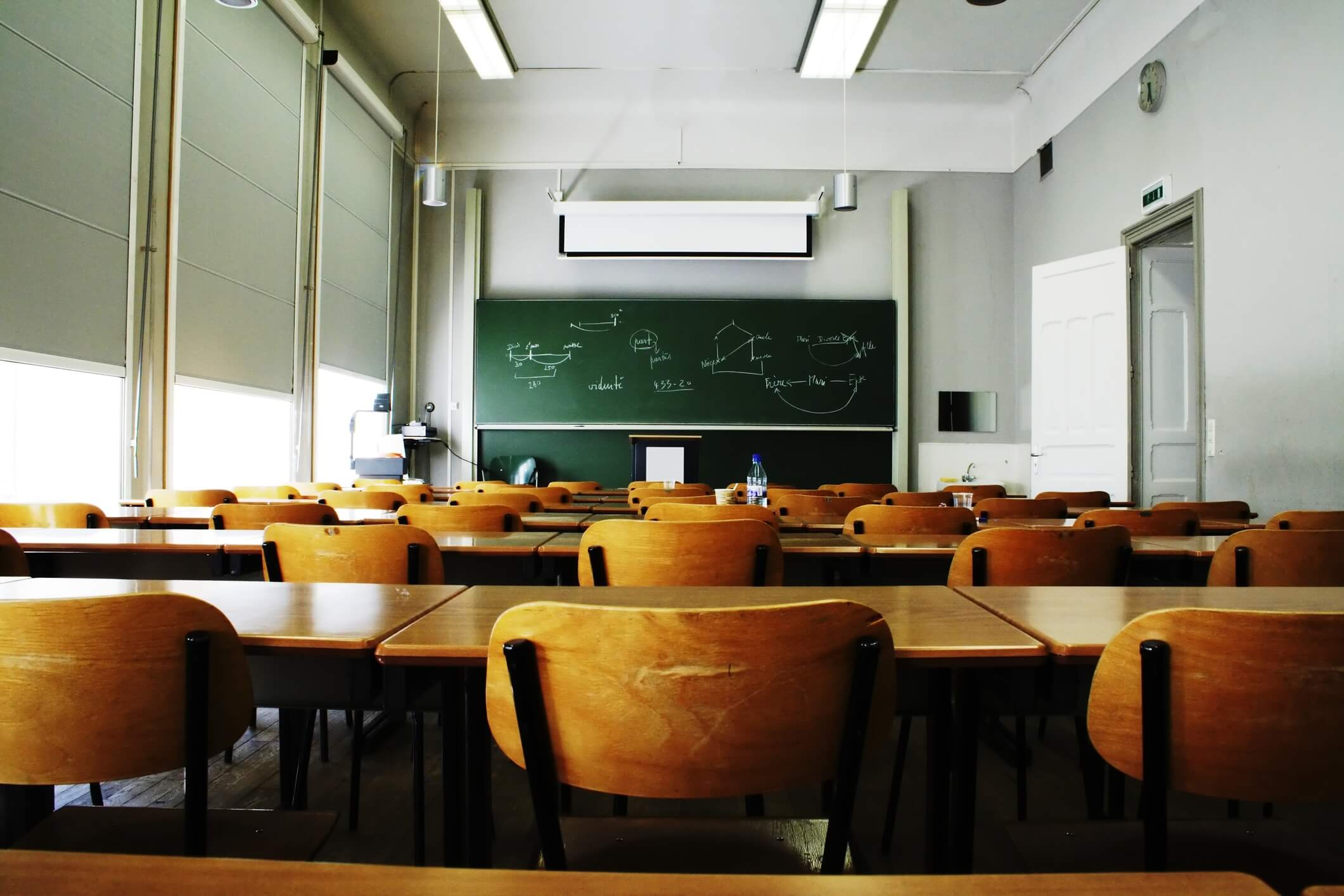 A large, empty classroom with wooden chairs.