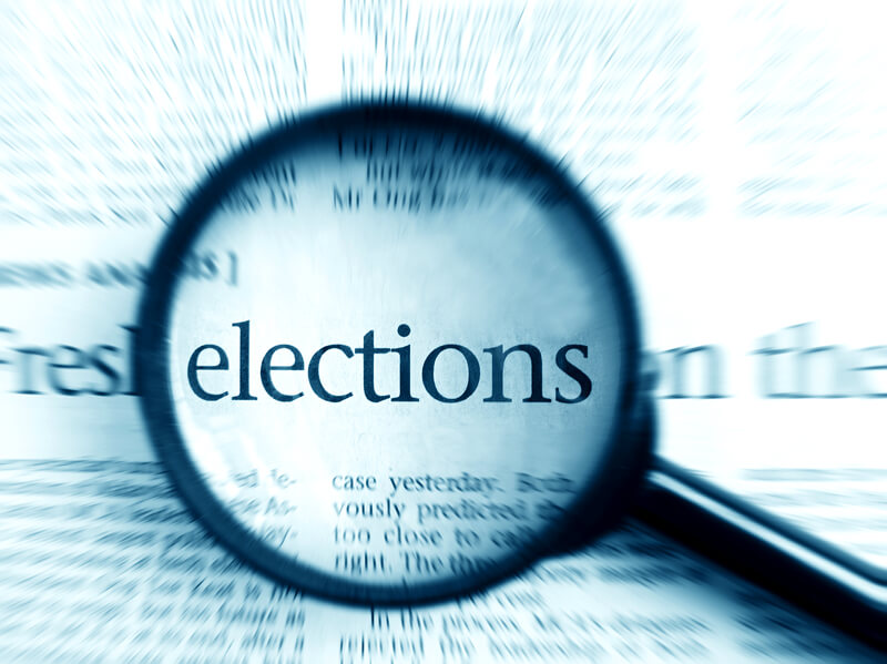 Election - elections word in focus. A concept image of the word elections focused by a magnifying glass. Radial blur to simplify background. Monochrome blue image. Politics concepts, copy space, nobody in picture.