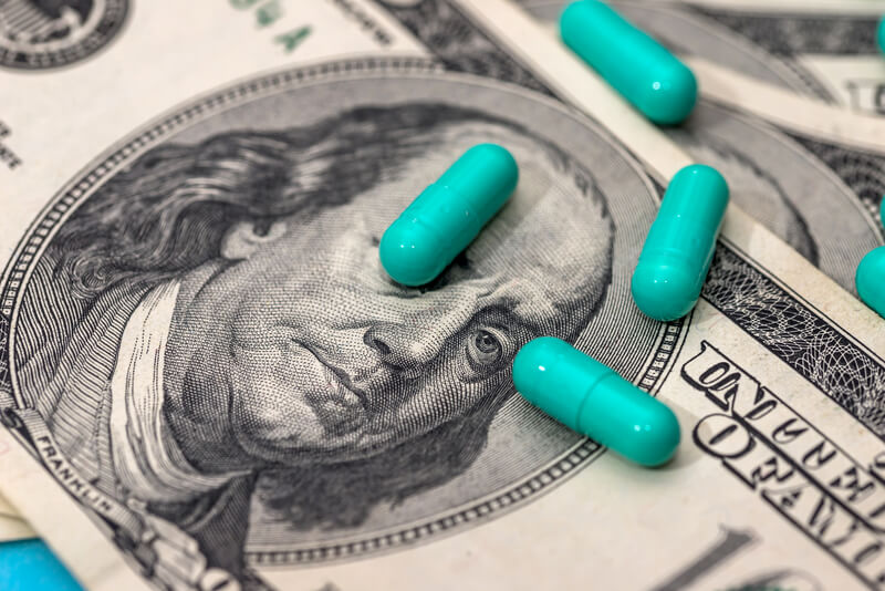 Medicines capsules on dollar bills close up