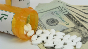 2026 Medicare part d. Prescription drug bottle spilled over stack of twenty dollar bills.