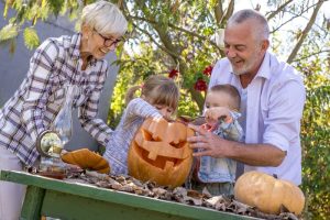 A closeup shot of grandparents helping children to carve a pumpkin for Halloween