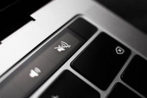 Kiev, Ukraine - August 9,2022: Silent mode sign on touch bar apple macbook pro close up. Fingerprint sensor next to the volume. Fingerprint sensor next to the volume buttons on the touchpad of the laptop.