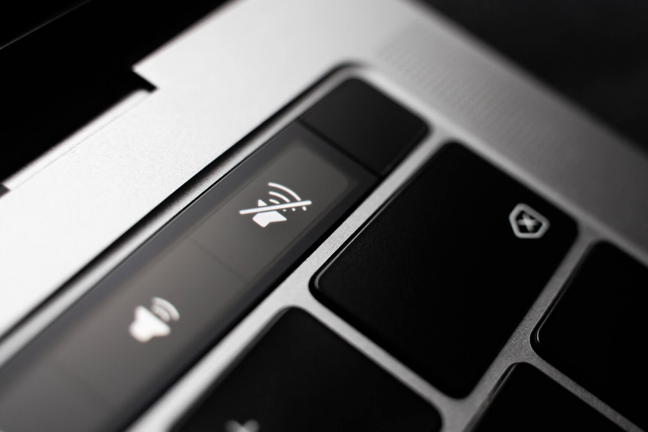 Kiev, Ukraine - August 9,2022: Silent mode sign on touch bar apple macbook pro close up. Fingerprint sensor next to the volume. Fingerprint sensor next to the volume buttons on the touchpad of the laptop.