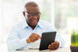Senior man reading the summary of benefits on his tablet and smiling.