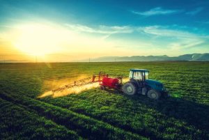Aerial drone view of farming tractor plowing and spraying on field