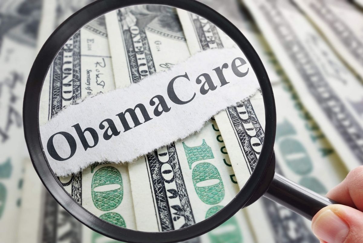 Obamacare and magnifying glass. Obamacare newspaper headline on cash with magnifying glass