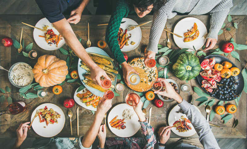 Friends clinking glasses at Thanksgiving Day with vegetarian meals.