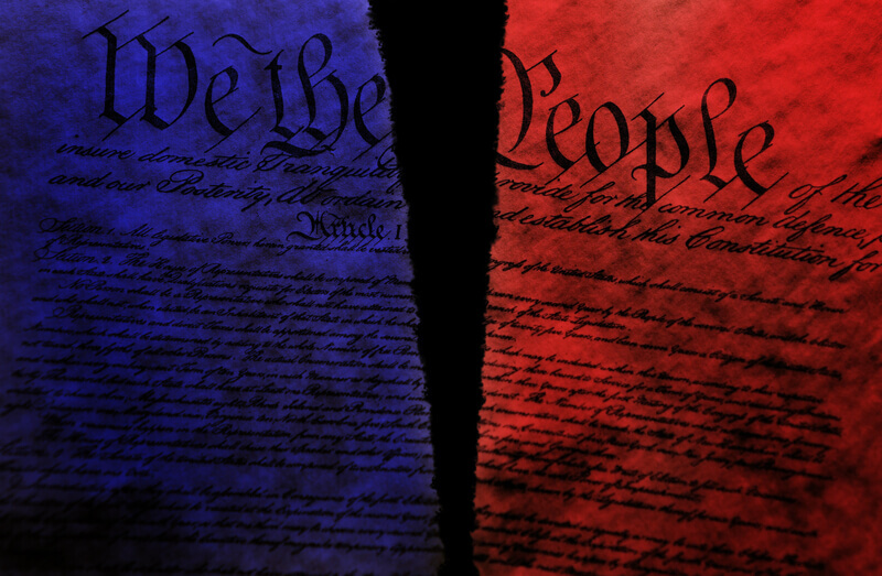 Torn US Constitution with red and blue split representing division in US politics.