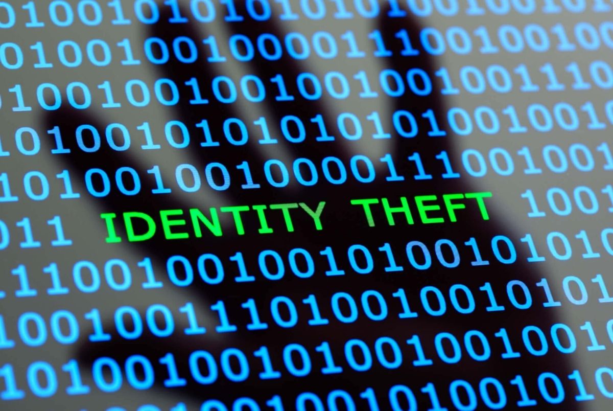 Identity theft online. Internet identity theft on a digital tablet with reflection of hackers hand concept for online digital crime