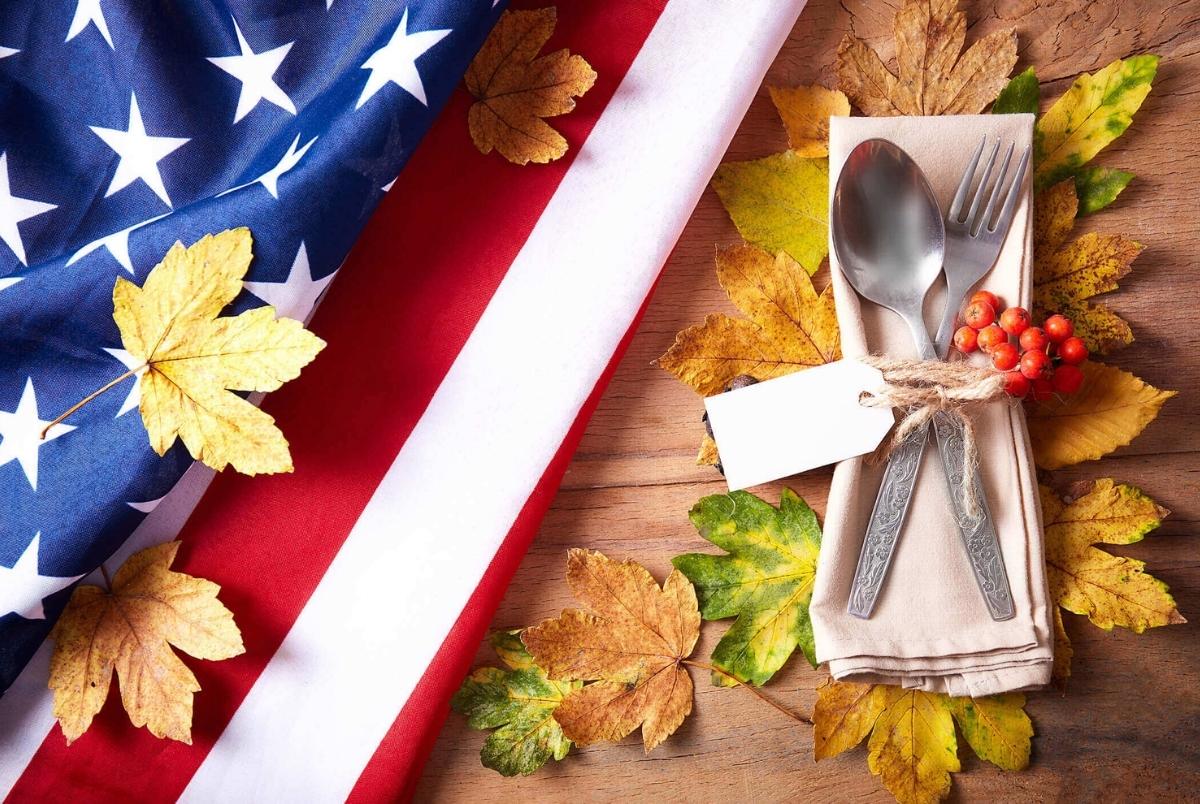 Thanksgiving autumn place setting with cutlery and arrangement of colorful fall leaves with american flag