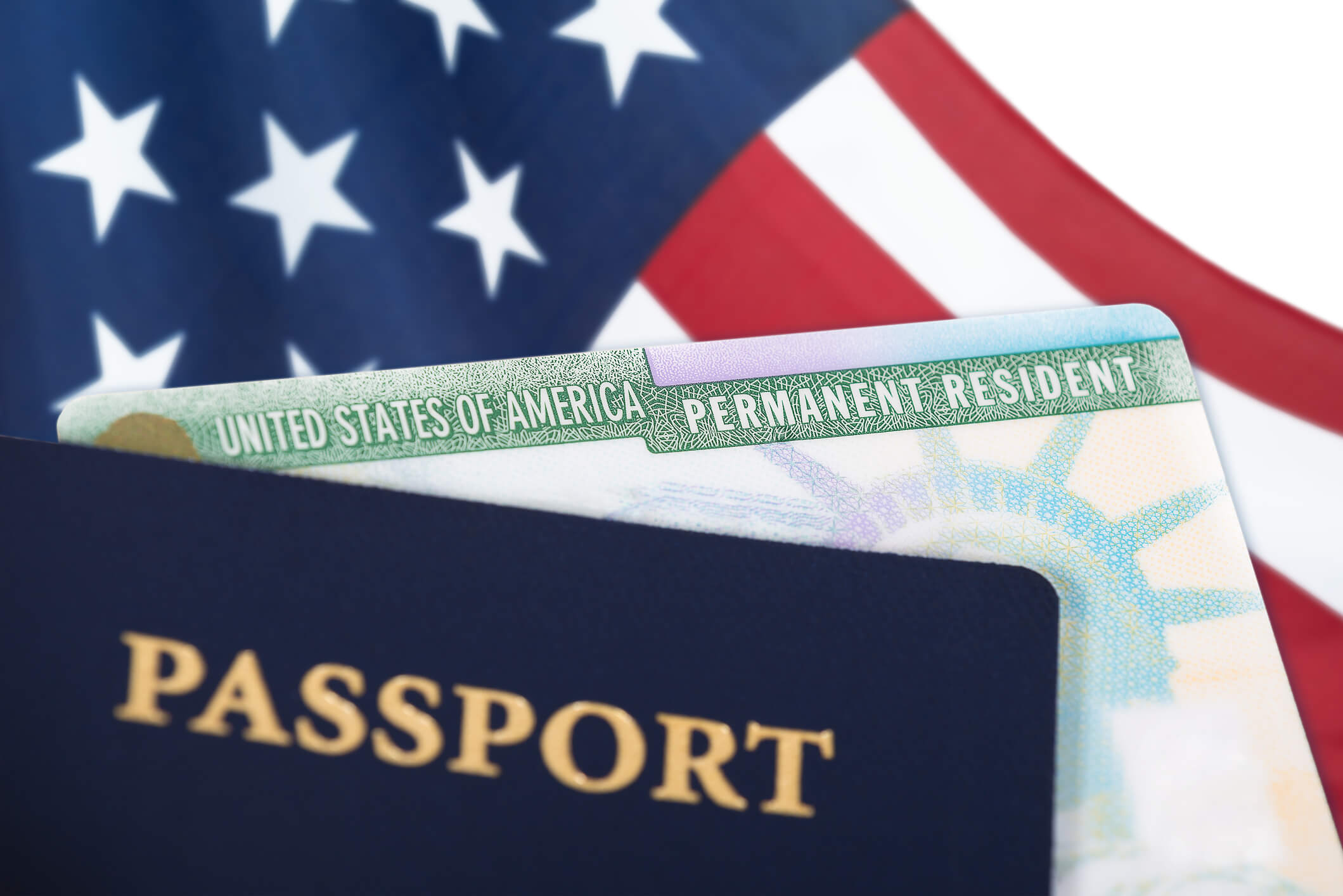 United States permanent resident card. United States of America permanent resident card, green card, displayed with a US flag in the background and a passport in the foreground. Immigration concept.