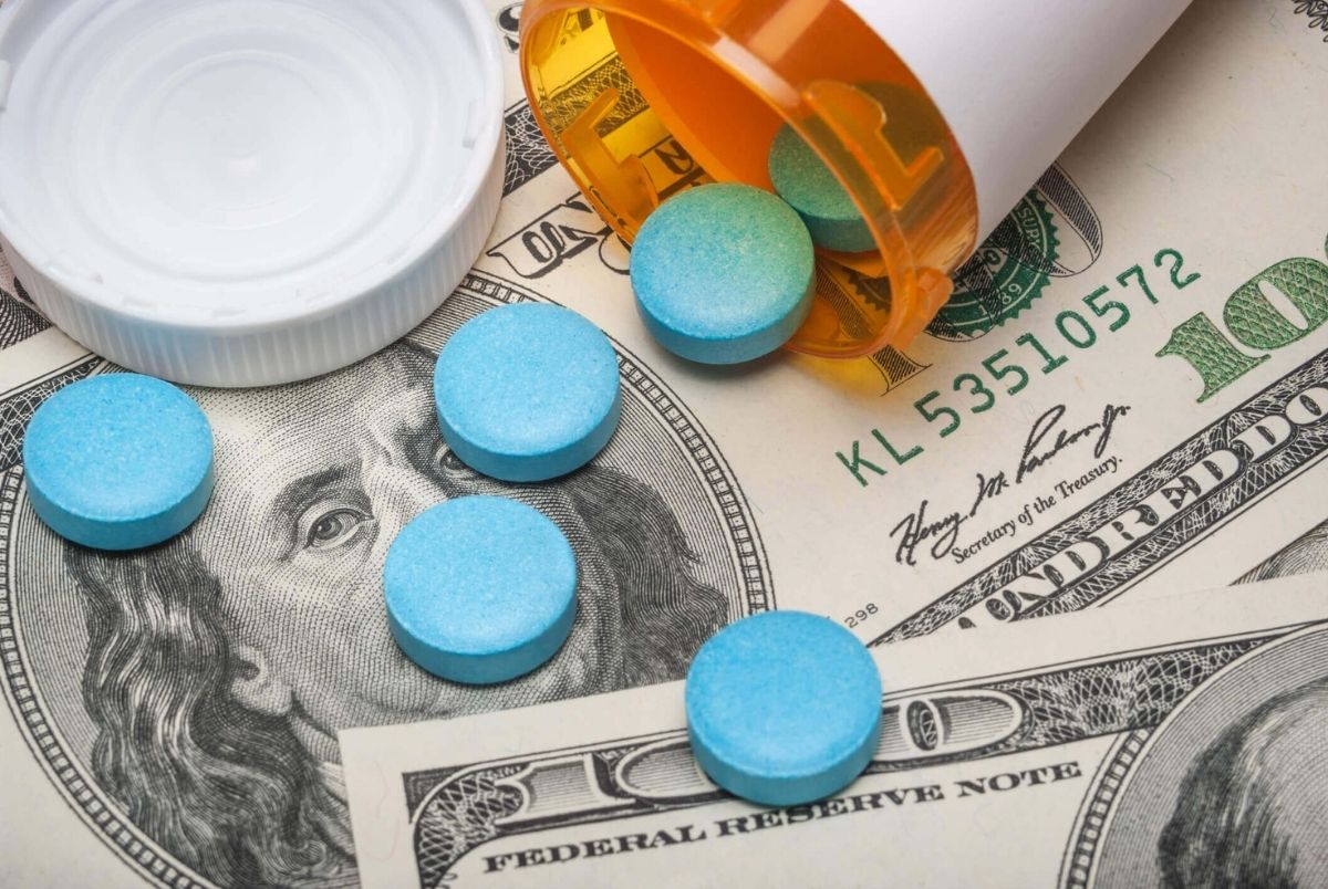 Prescription medicine and money. Pills spilling out of a prescription bottle on 100 dollar paper currency