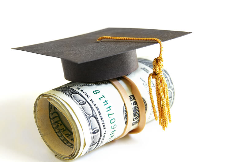 Grad money. Mini graduation cap on a roll of money