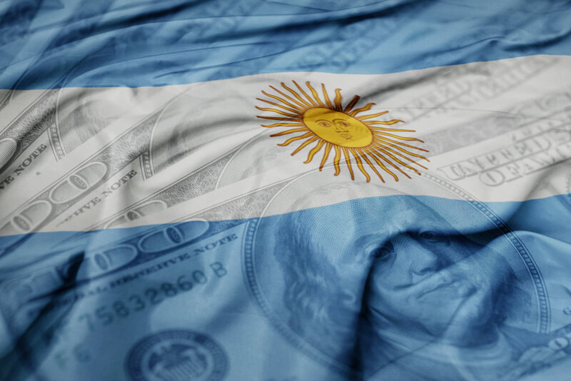 Waving colorful flag of argentina on the dollar money background. finance concept. macro shot