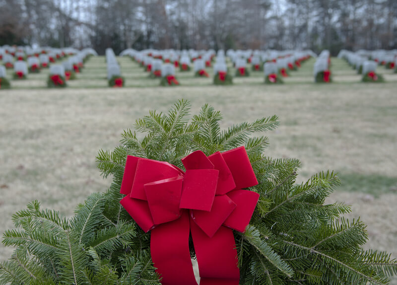 Detailed view of a wreath that has been placed on all graves in a military cemetery. The marking of each grave in the cemetery with a wreath as a way to remember a veteran.