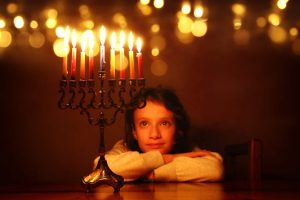 Small child looking at a fully lit menorah