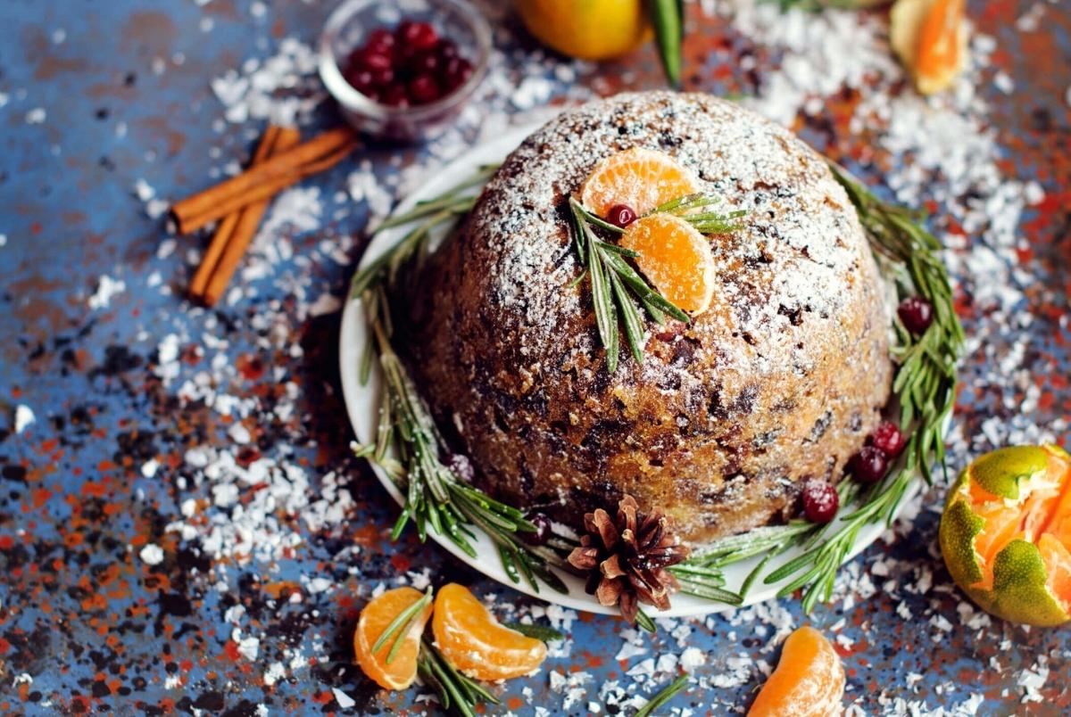Plum pudding on blue vintage background. Plum pudding with mandarins and berries on blue vintage background. Copyspace