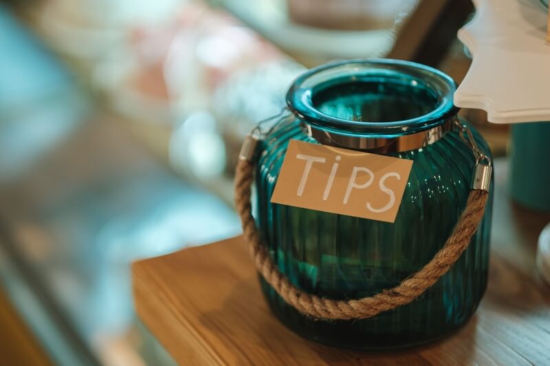 The inscription tips on a glass antique jar. The inscription tip on a glass antique jar with a sign on a rope in a restaurant, close-up, selective focus horizontal shot.