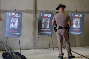 A Florida Highway Patrol officer looks at pictures of alleged criminal aliens before a press conference at the ICE, Enforcement and Removal Operations building on November 13, 2025 in Miramar, Florida.