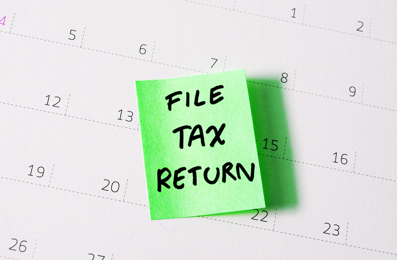 Hand written reminder to file tax return on green note calendar background
