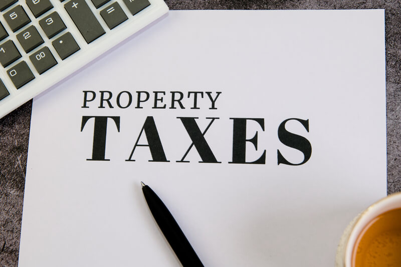 Key insights on property taxes for homeowners. A document on property taxes sits by a calculator and coffee, symbolizing financial planning