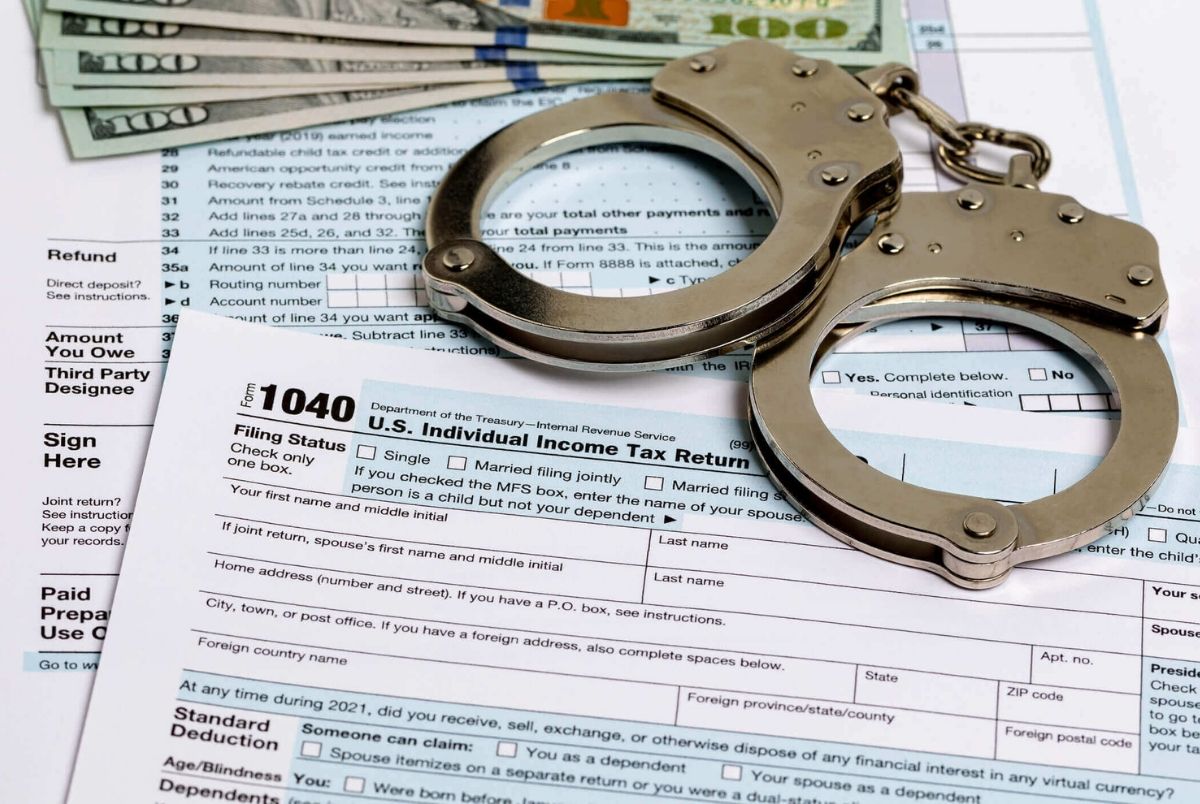 Income tax return documents and handcuffs. Tax evasion, crime and fraud concept.