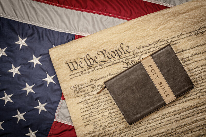 Holy bible on constitution and American Flag. A holy bible and crucifix rest atop the United States Constitution and American flag, which is emblematic of freedom of religion without persecution