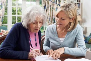Female Neighbor Helping Senior Woman To Complete Form