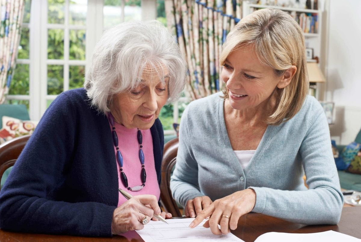 Female Neighbor Helping Senior Woman To Complete Form
