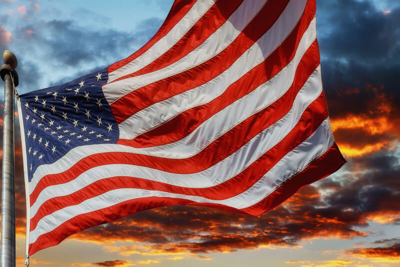 Flag USA over beautiful Sunset sunrise with clouds, in pink and purple shades